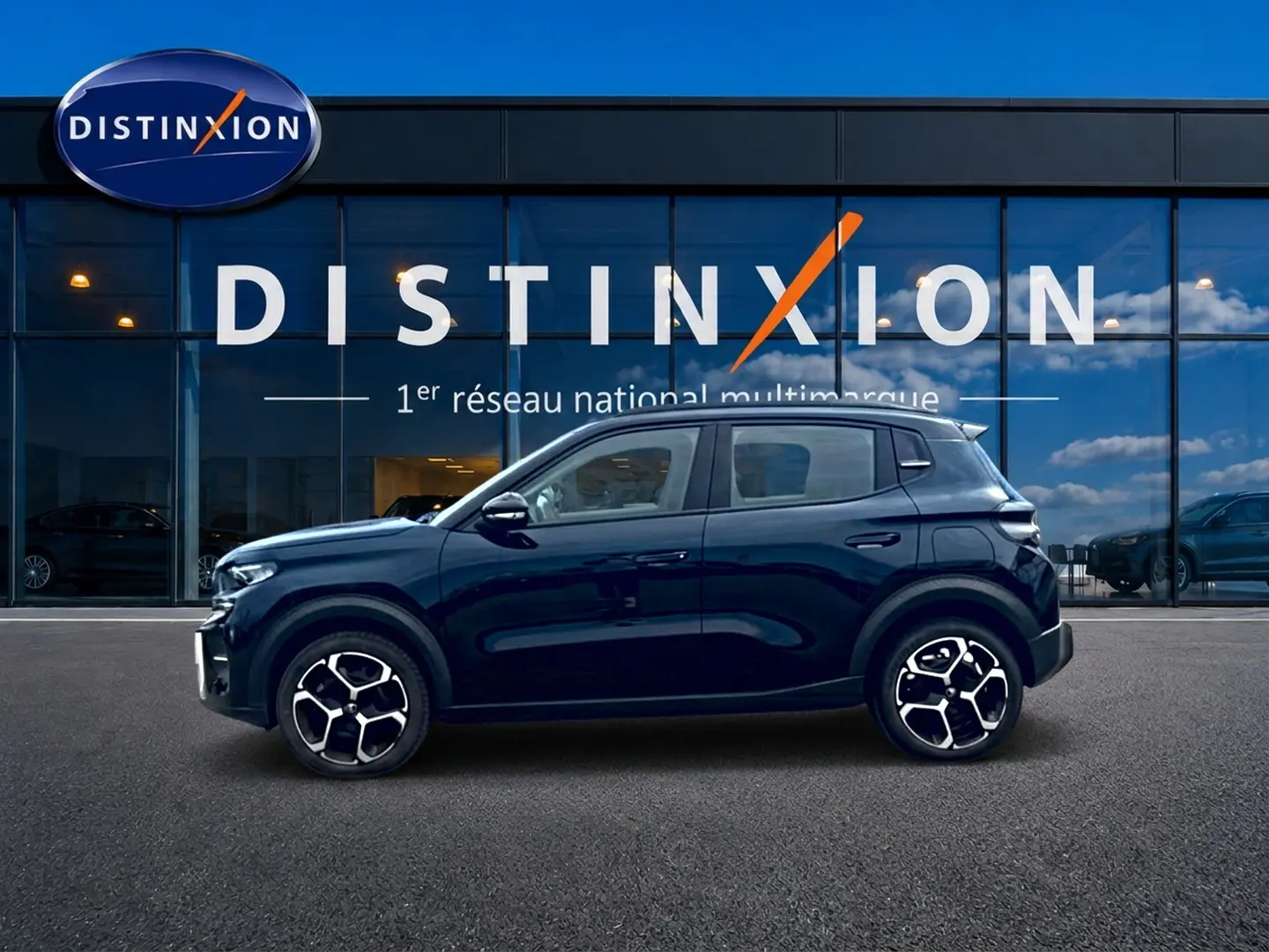 Profil côté gauche de la Citroën C3 113 Plus électrique noire 2025 avec jantes distinctives devant un showroom Distinxion.