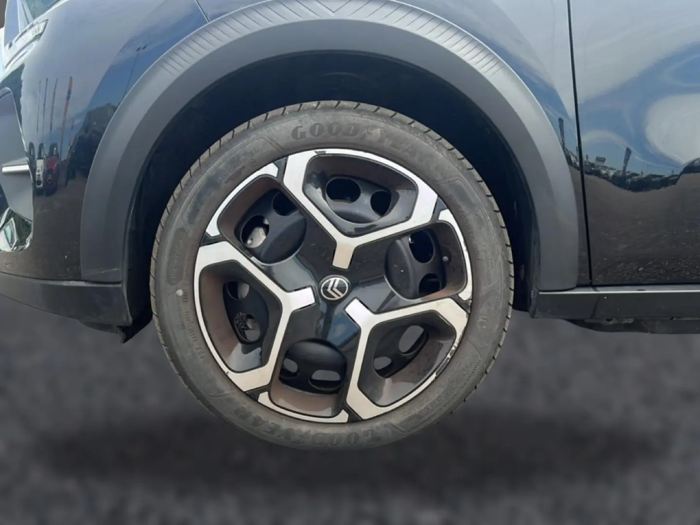 Gros plan sur la roue avant gauche noire d'une Citroën C3 113 Plus électrique 2025 avec jante au design moderne bicolore.