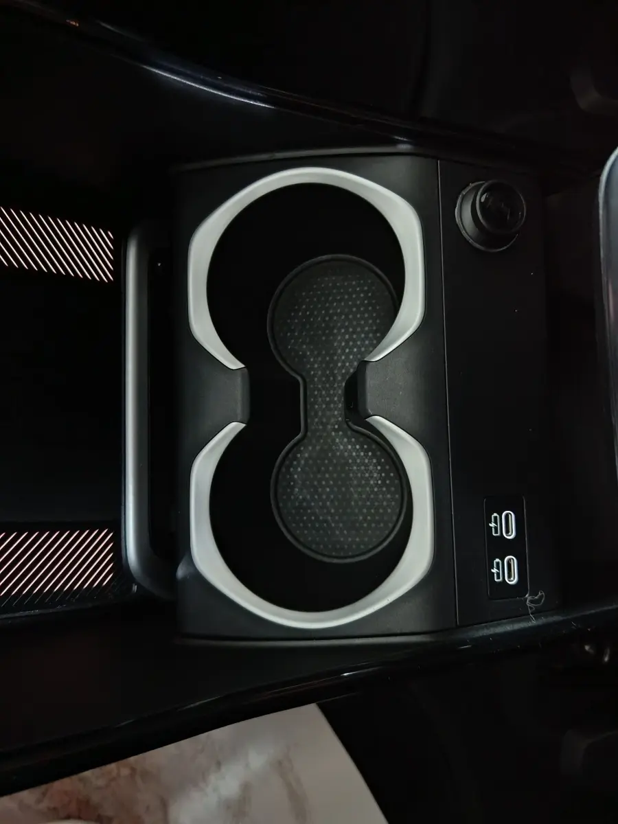 Gros plan sur les porte-gobelets noirs et gris du BMW X1 xDrive25e M Sport 2024, avec commandes éclairées à côté.