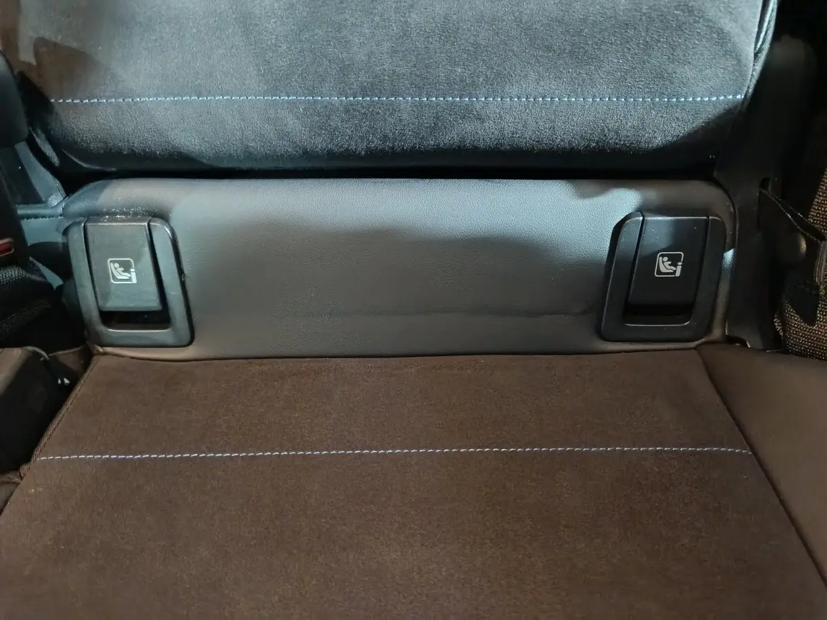 Détail des commandes Isofix sur la banquette arrière en tissu noir et surpiqûres bleues du BMW X1 blanc xDrive25e M Sport 2024.