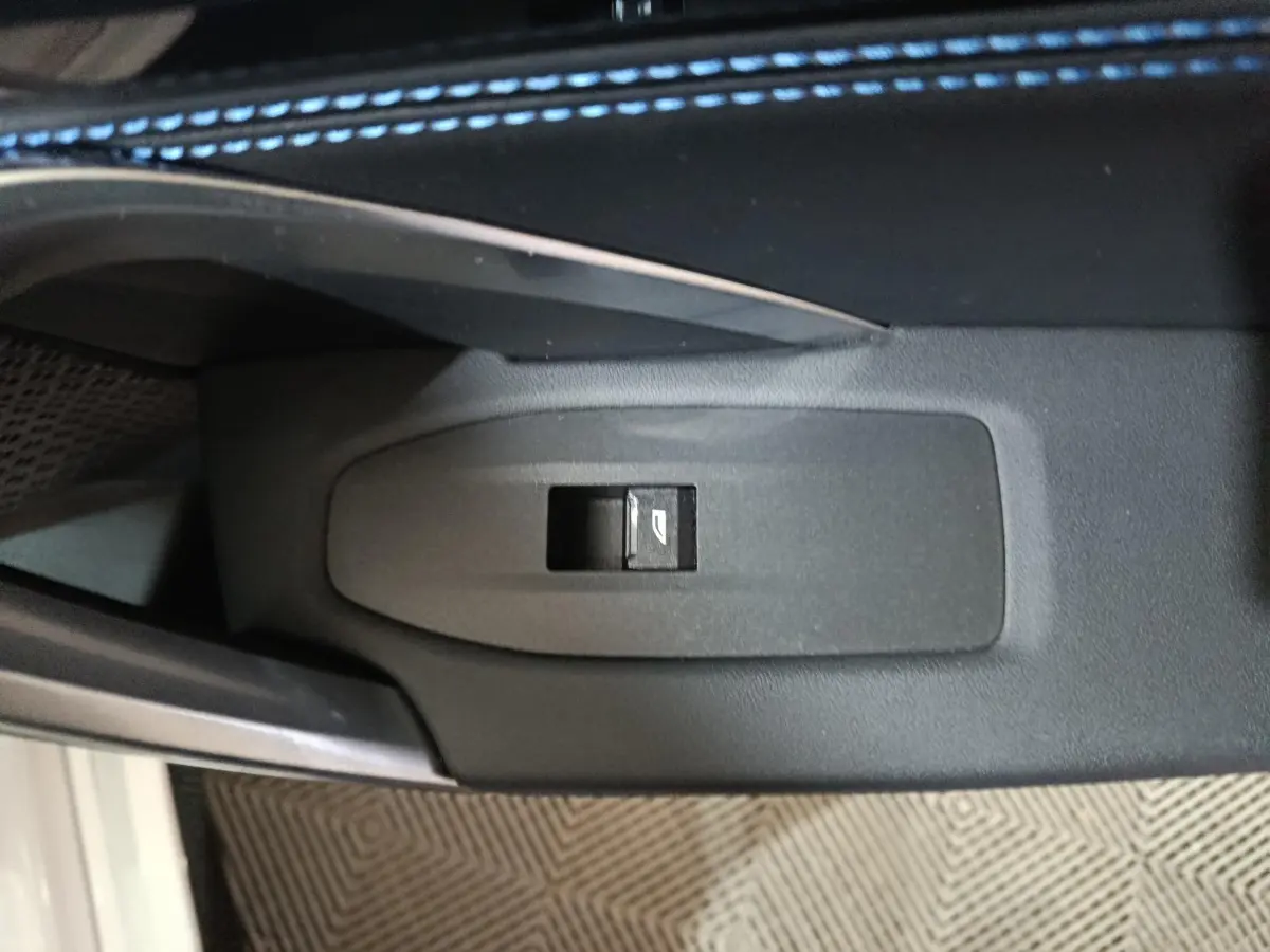 Bouton de commande de lève-vitre électrique sur la porte intérieure d’un BMW X1 blanc, vue rapprochée.