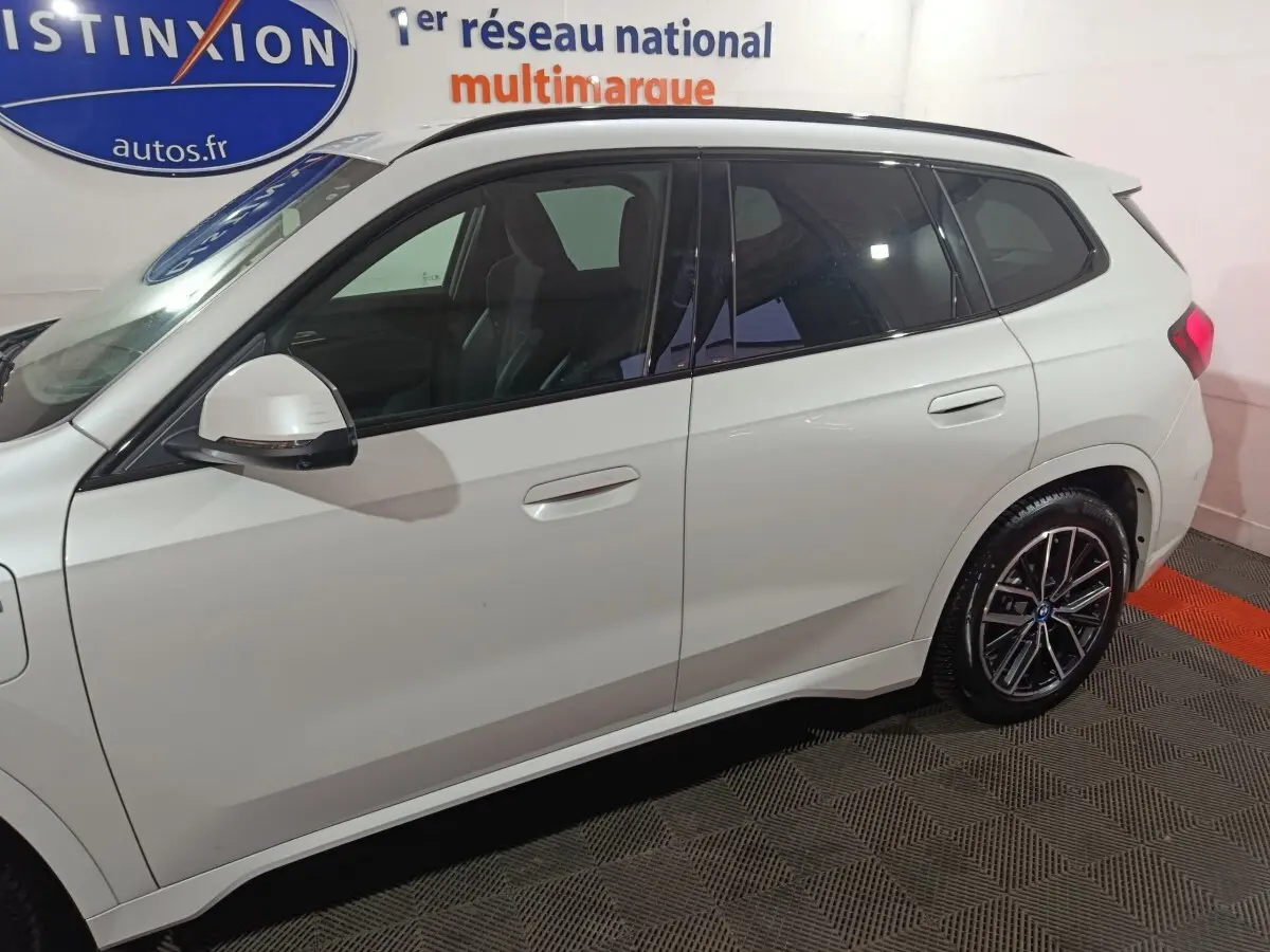 Vue latérale droite d'un BMW X1 blanc 2024 xDrive25e M Sport avec jantes noires et vitres teintées.
