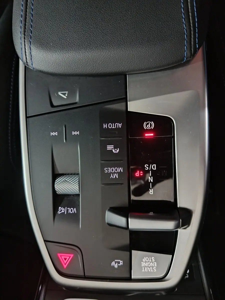 Gros plan sur la console centrale noire et grise du BMW X1 blanc 2024 avec levier de vitesses et commandes tactiles.