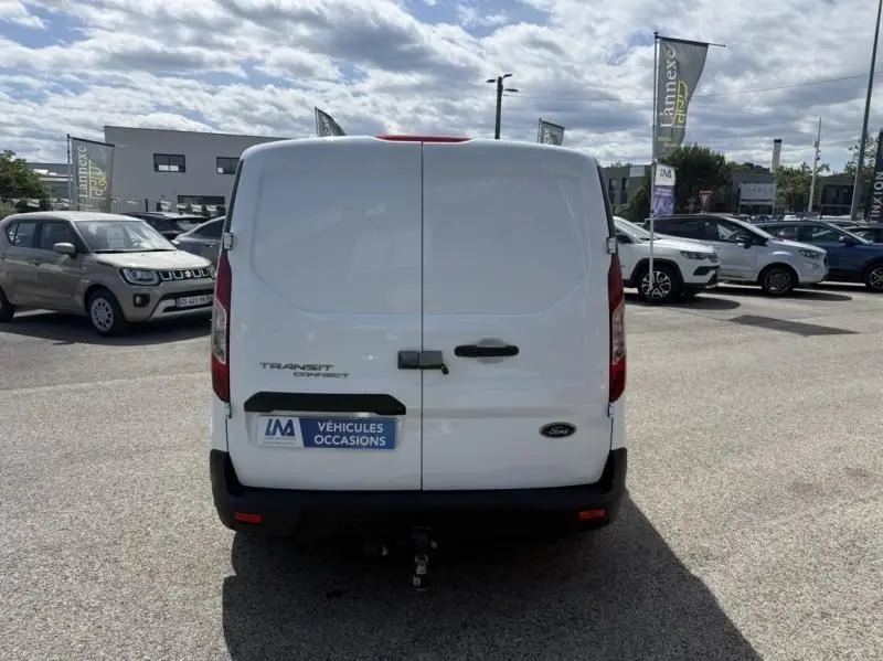 Vue arrière d’un Ford Transit Connect blanc glacier, avec porte double et attelage visible en bas.
