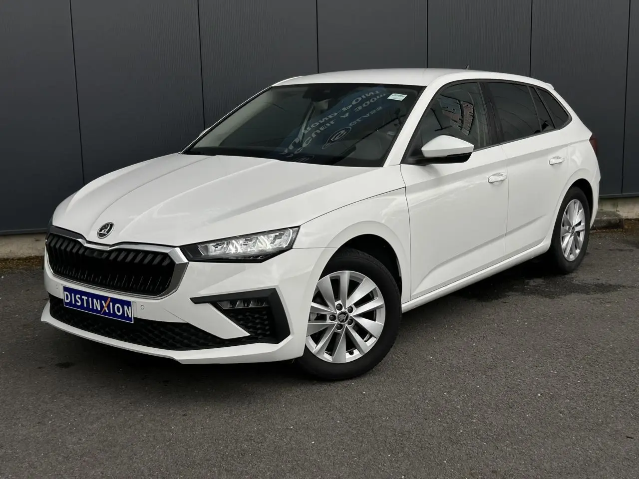 Vue 3/4 avant droite d'une Skoda Scala blanche Candy avec jantes alliage et vitres latérales surteintées.