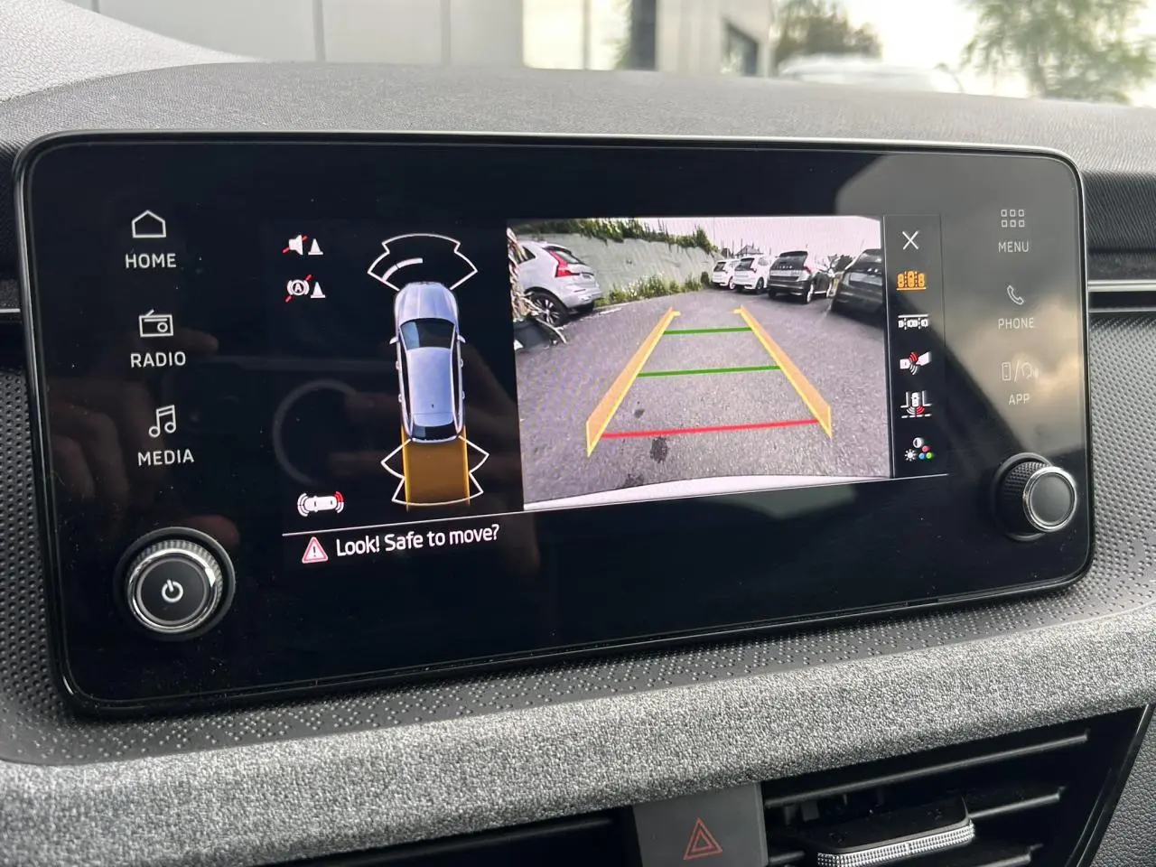 Écran central de la Skoda Scala blanc montrant la caméra de recul avec lignes de guidage colorées.