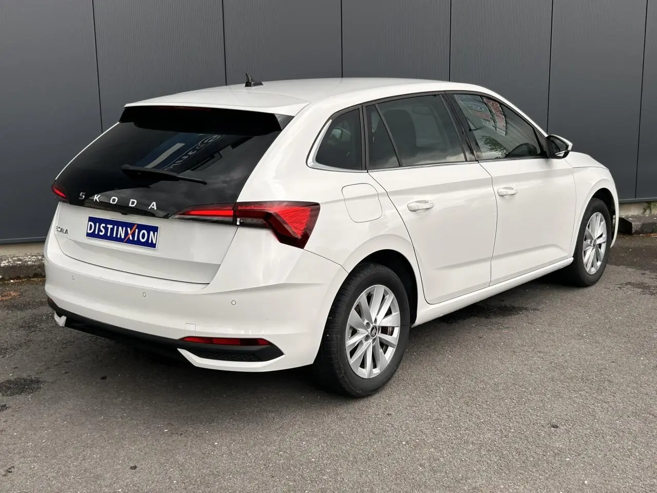 Vue 3/4 arrière droite d'une Skoda Scala blanc Candy avec vitres arrière surteintées et jantes alliage 16 pouces.