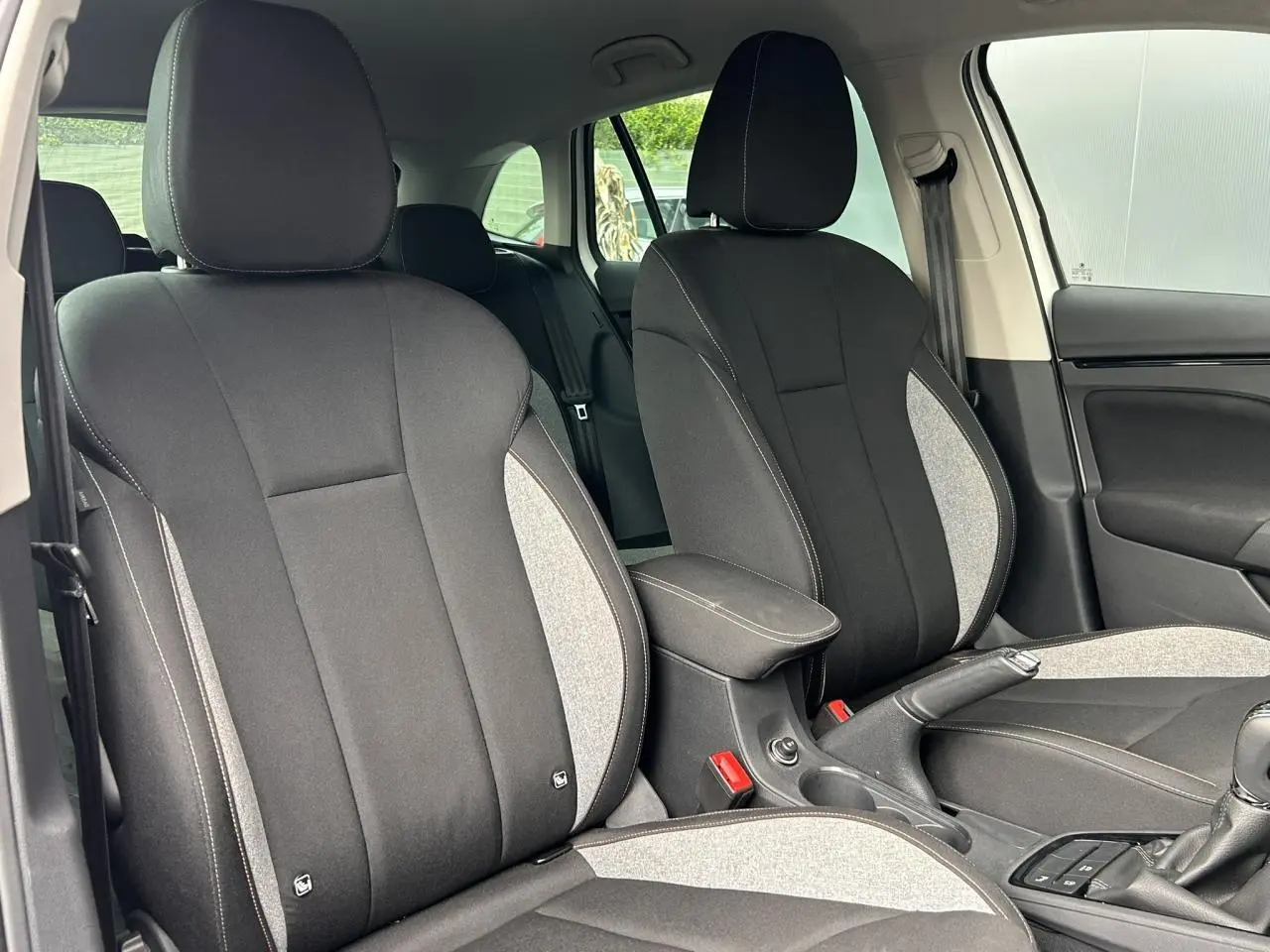 Vue intérieure sur les sièges avant tissu noir et gris du Skoda Scala TSI 116 DSG7 Sélection, avec accoudoir central.