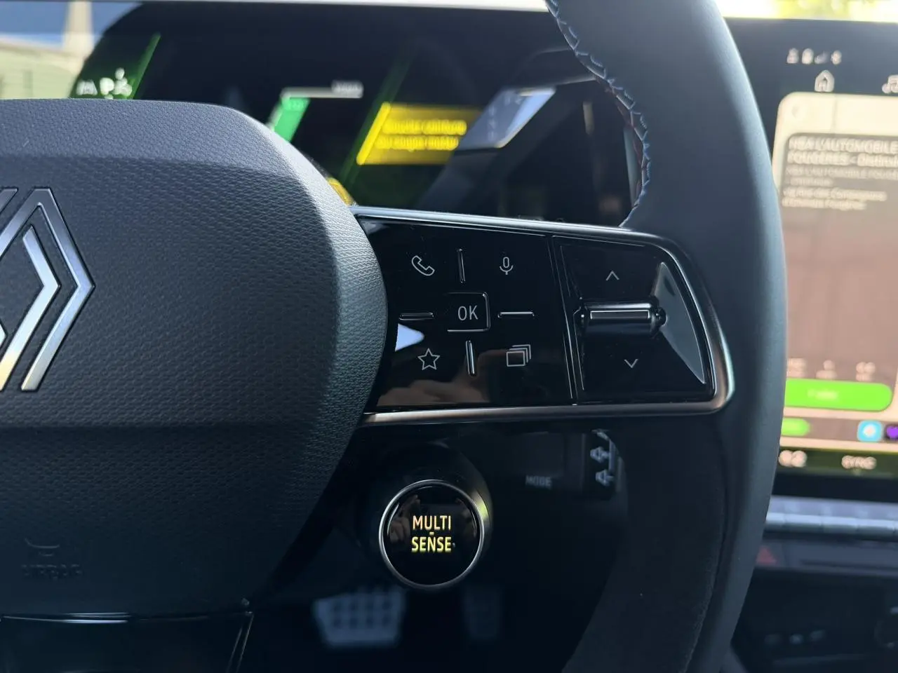 Gros plan sur le volant noir avec surpiqûres bleues et bouton Multi-Sense du Renault Rafale E-Tech hybride 2026.