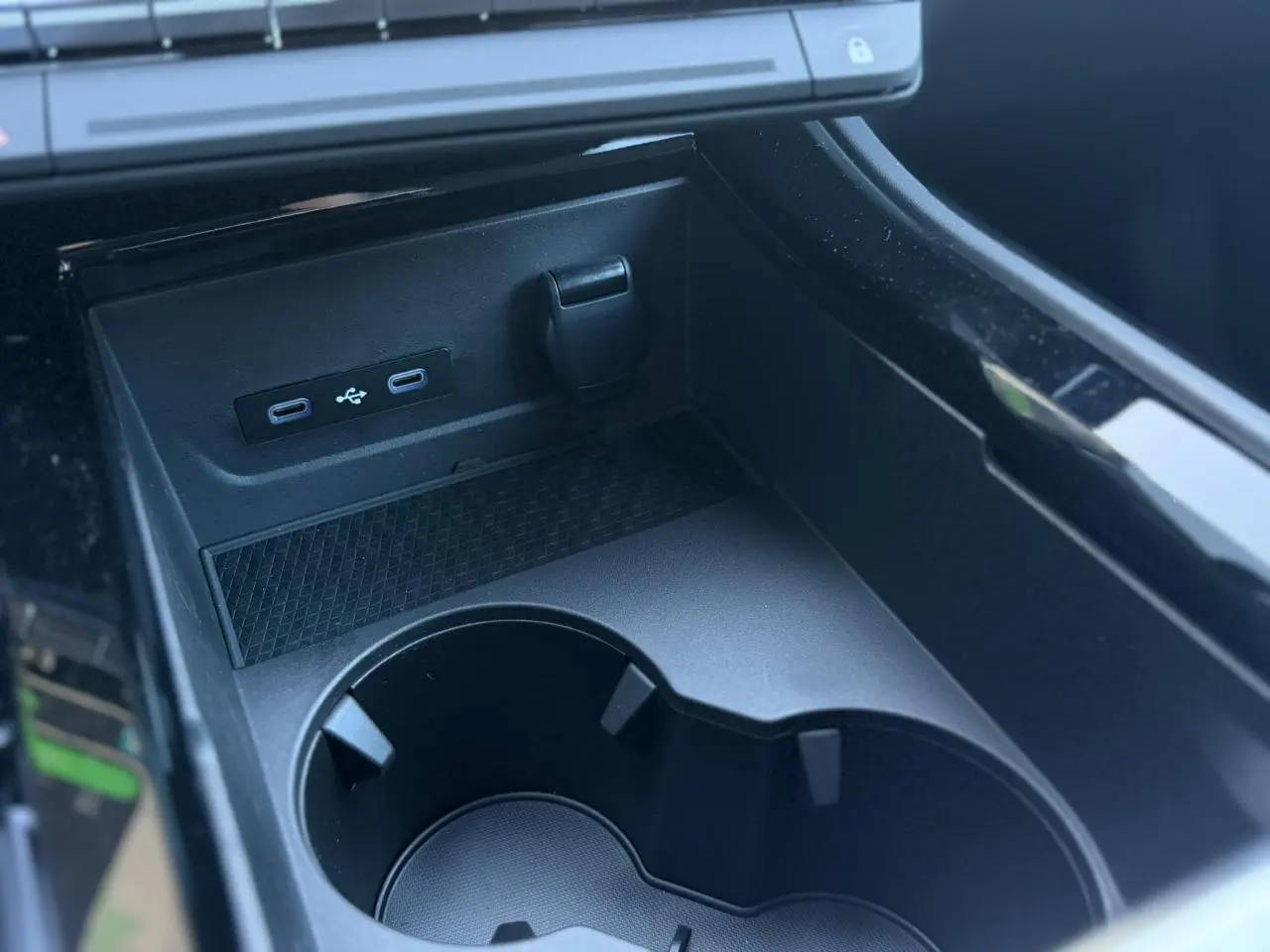 Gros plan sur la console centrale noire du Renault Rafale avec ports USB-C et prise 12V, porte-gobelets intégrés.