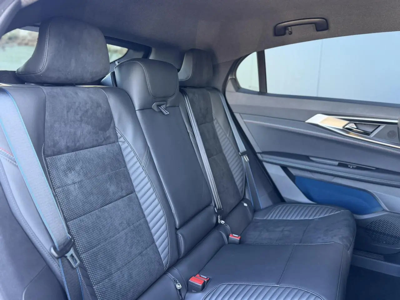 Vue intérieure côté droit des sièges arrière en cuir et Alcantara gris avec surpiqûres bleu, blanc, rouge sur Renault Rafale E-Tech.