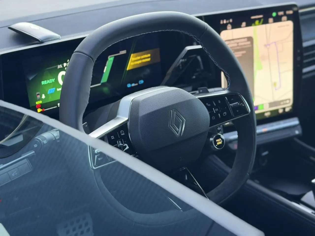 Vue rapprochée du volant Alcantara avec logo Renault et tableau de bord numérique du Renault Rafale E-Tech 2026.