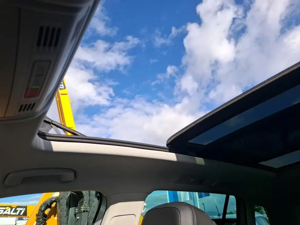 Vue intérieure du toit ouvrant panoramique du Volkswagen Tiguan gris clair 2022, avec ciel bleu visible à travers le verre.