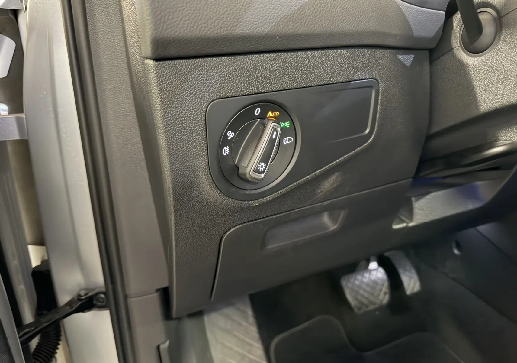 Détail du commodo d’éclairage à gauche du volant dans l’habitacle noir du Volkswagen Tiguan gris clair 2022.