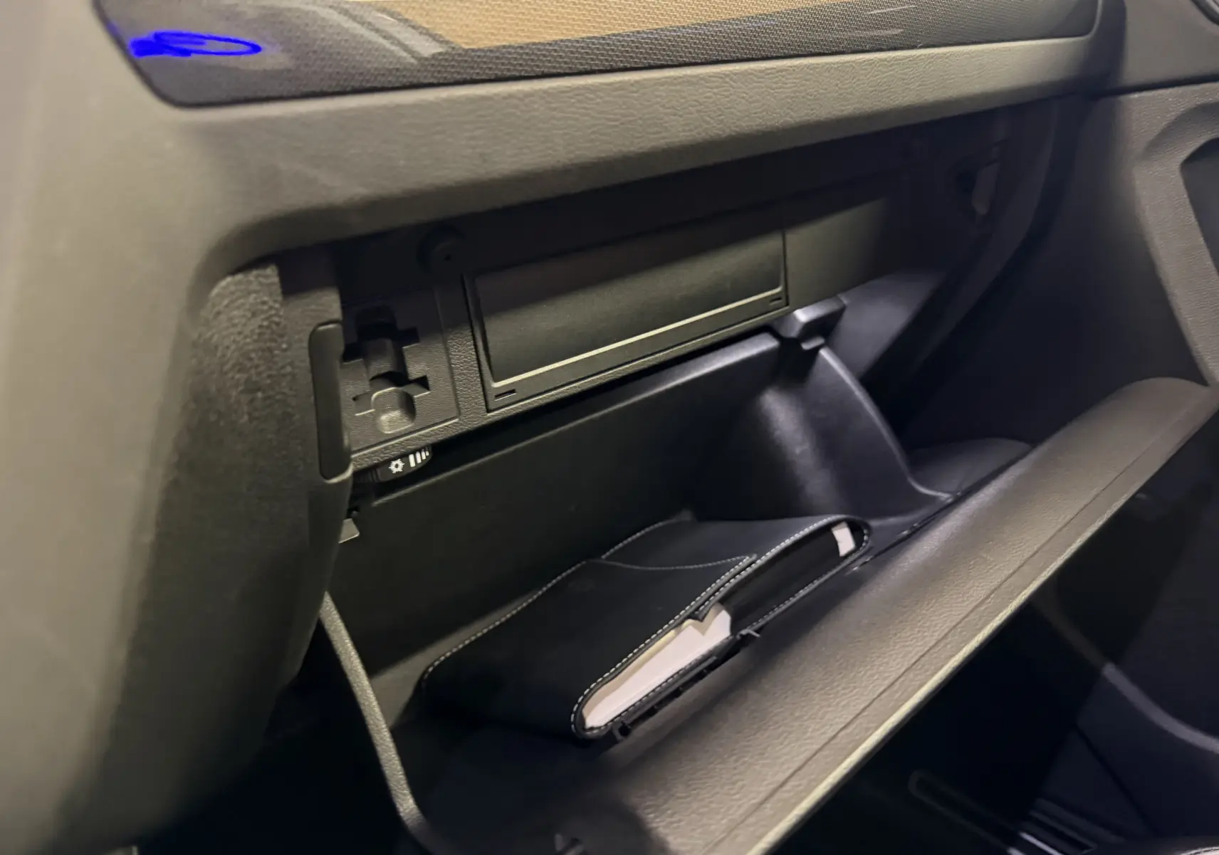 Vue rapprochée de la boîte à gants ouverte du Volkswagen Tiguan gris clair 2022, avec un carnet noir à l'intérieur.
