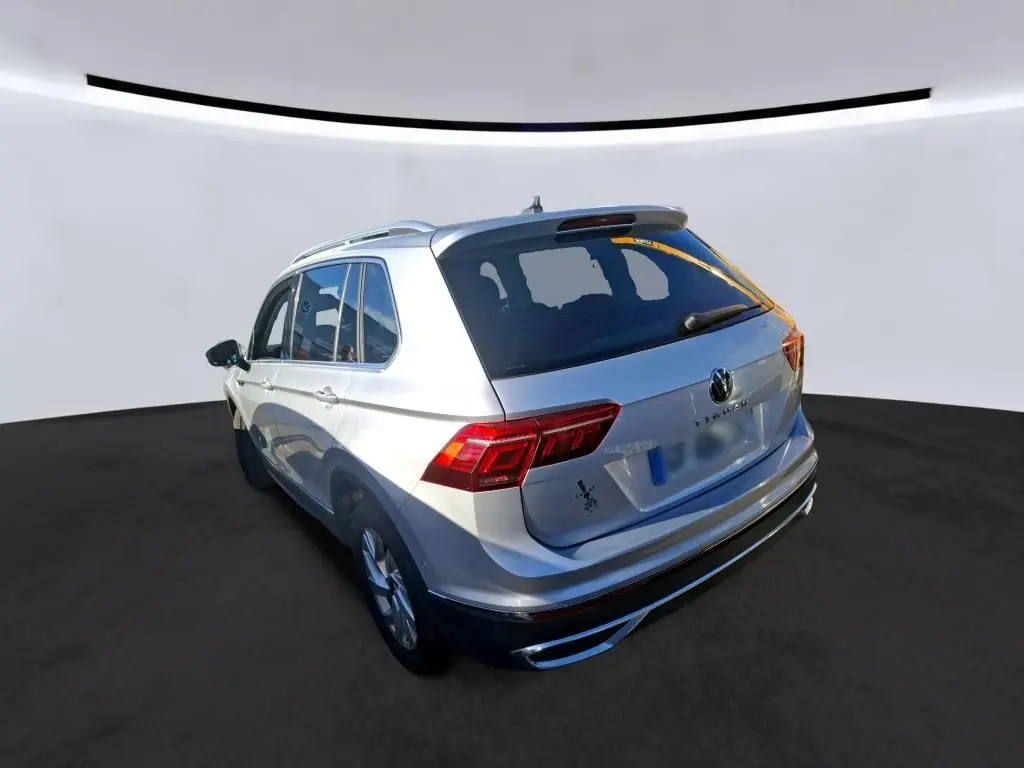 Vue 3/4 arrière droite d'un Volkswagen Tiguan gris clair 2022 avec feux arrière LED et toit ouvrant apparent.