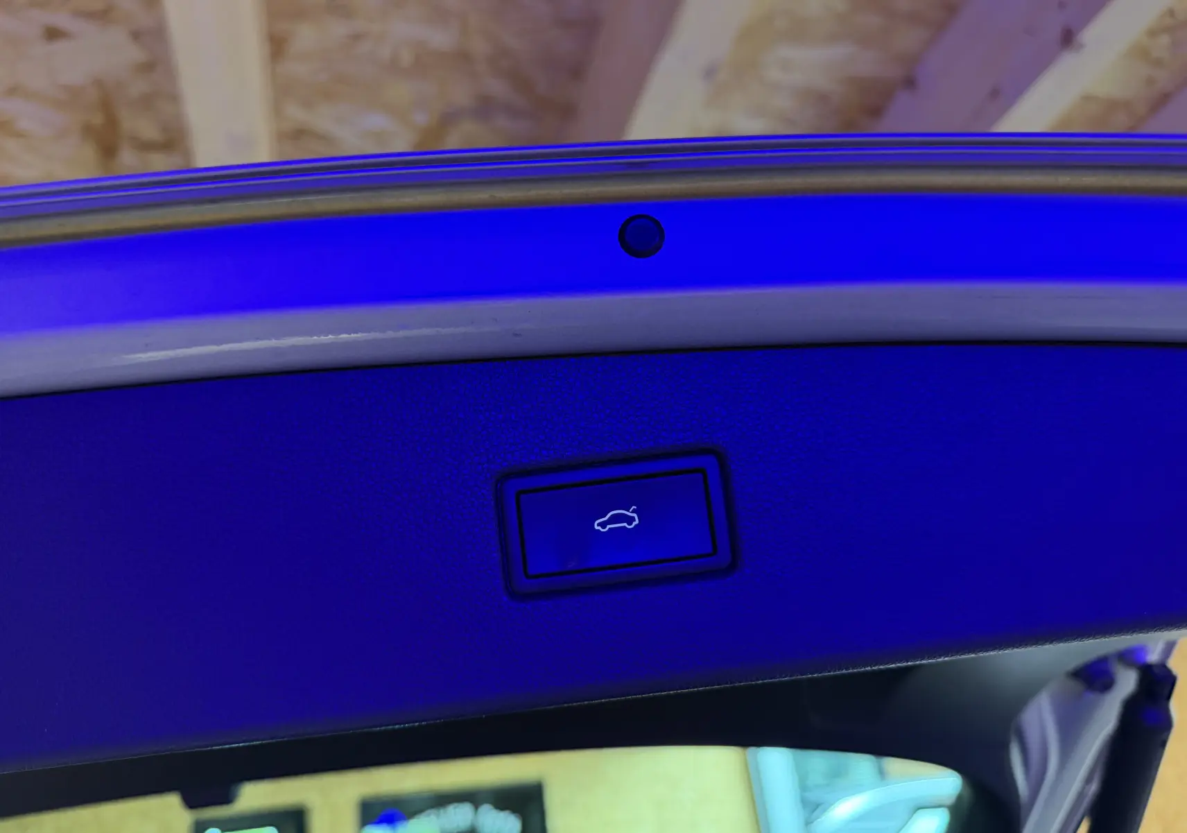 Bouton d'ouverture électrique du coffre sur la partie intérieure de la porte arrière d'un Volkswagen Tiguan gris clair 2022.