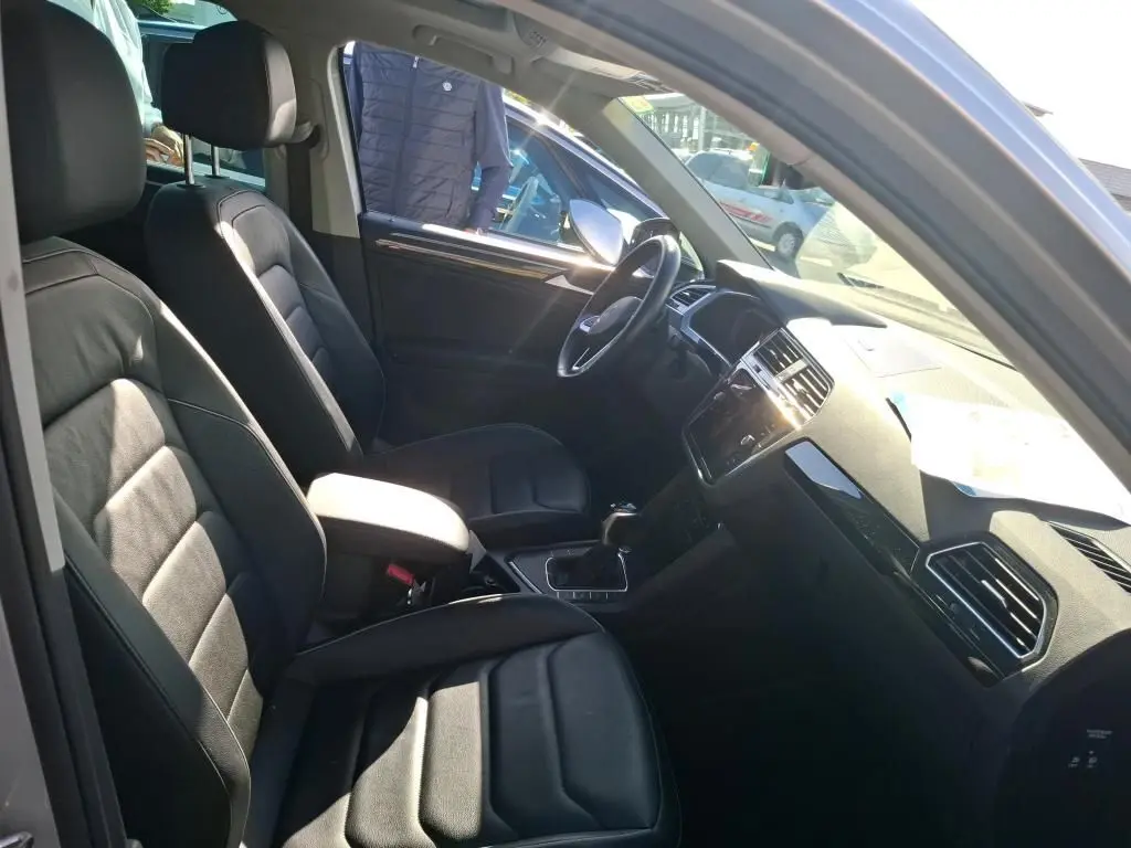 Vue intérieure côté conducteur du Volkswagen Tiguan 1.4 e-Hybrid 2022 avec sièges en tissu noir et tableau de bord moderne.