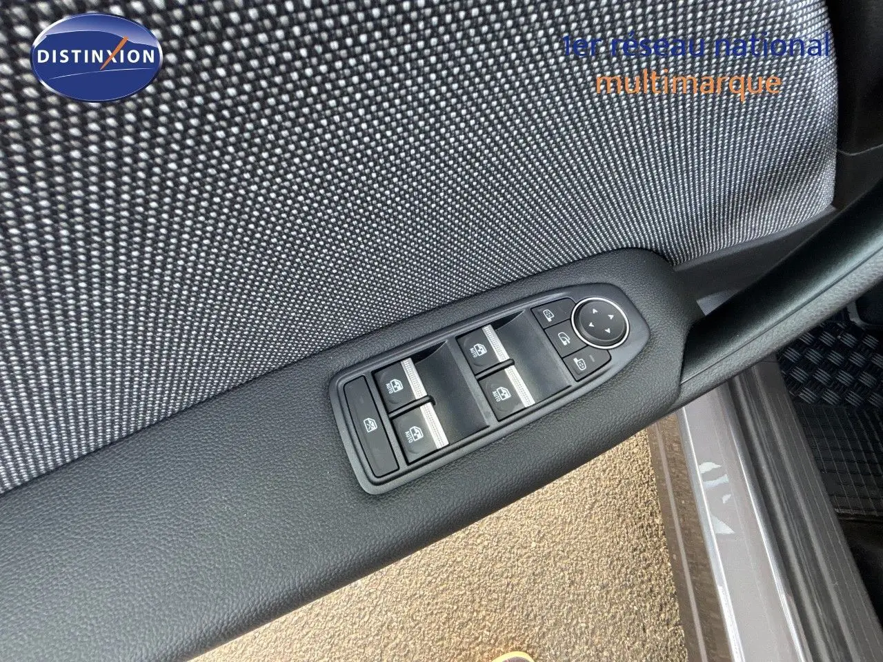 Gros plan sur les commandes des vitres électriques côté conducteur du Renault Symbioz gris Cassiopée métal, intérieur tissu.