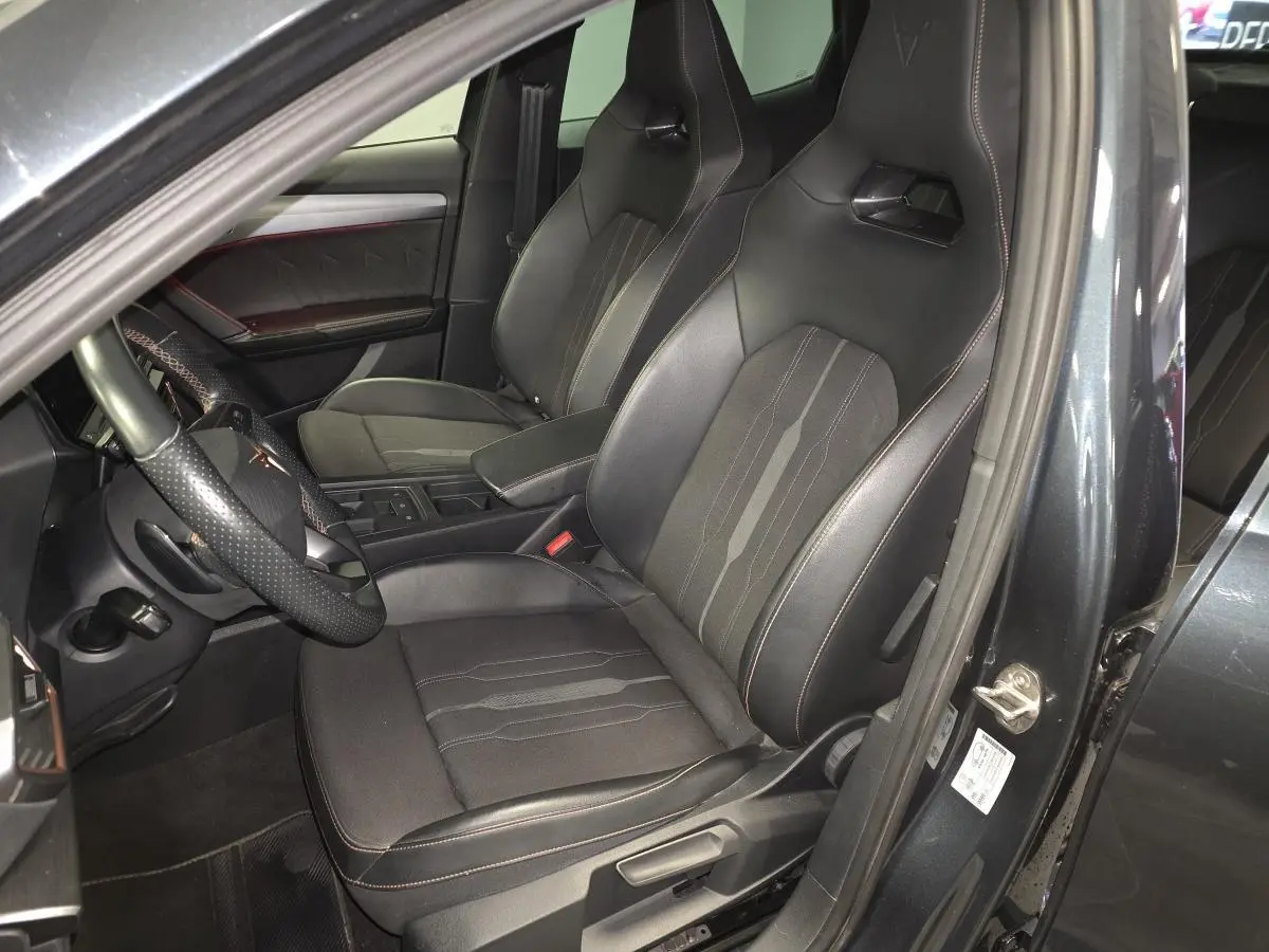 Intérieur du Cupra Formentor 1.4 e-Hybrid 2024 en gris, vue côté conducteur sur sièges baquets noirs avec surpiqûres cuivre.