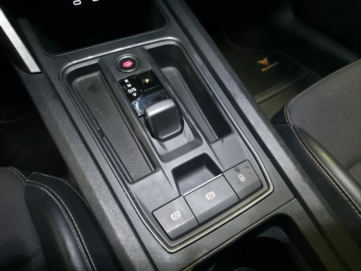 Vue rapprochée de la console centrale noire du CUPRA Formentor 1.4 e-Hybrid avec levier de boîte automatique et boutons fonctionnels.