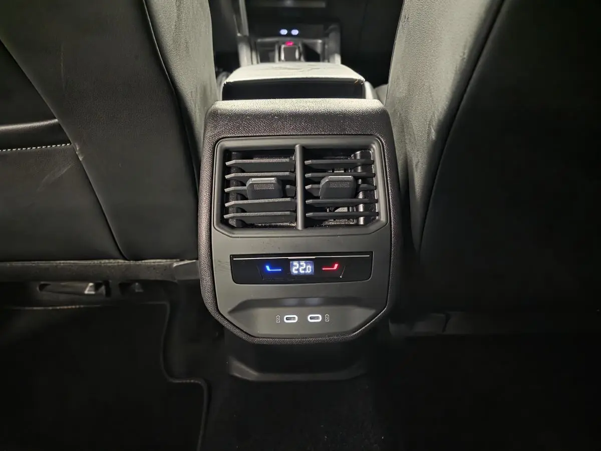 Vue rapprochée de la console arrière noire du CUPRA Formentor gris avec commandes climatisation et prises USB-C éclairées.