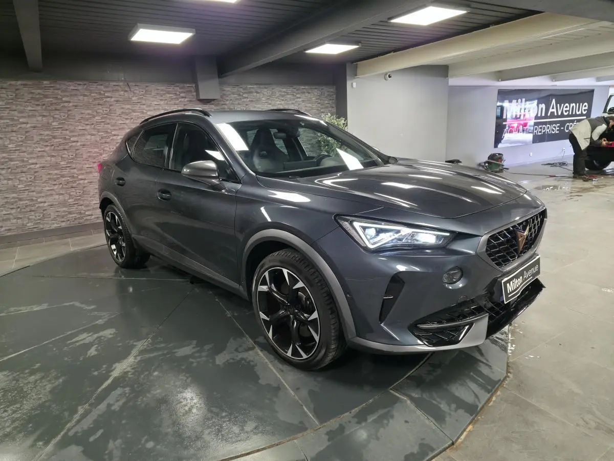 CUPRA Formentor gris magnétique en 3/4 avant droit, avec jantes alliage noires et éclairage LED allumé.