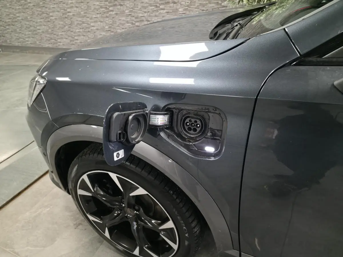 Vue de profil avant droit du CUPRA Formentor gris avec prise de recharge hybride ouverte au-dessus de la roue.
