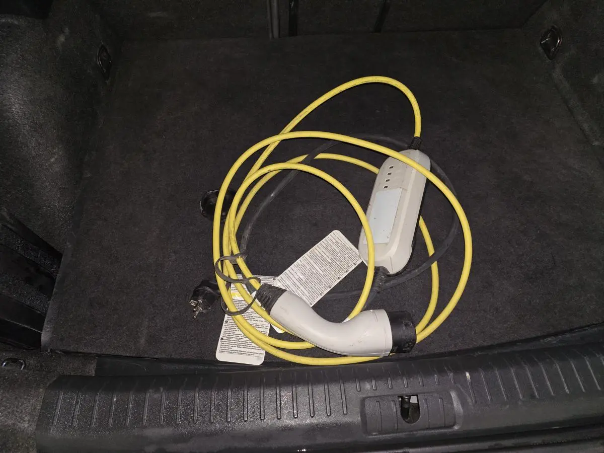 Gros plan sur le câble de recharge jaune dans le coffre noir d’un CUPRA Formentor hybride rechargeable 2024.