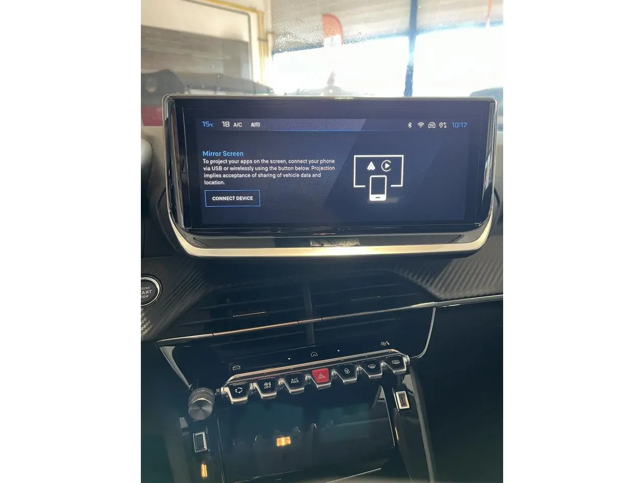 Vue intérieure du tableau de bord de la Peugeot 208 2024, écran tactile et commandes centrales en finition carbone.