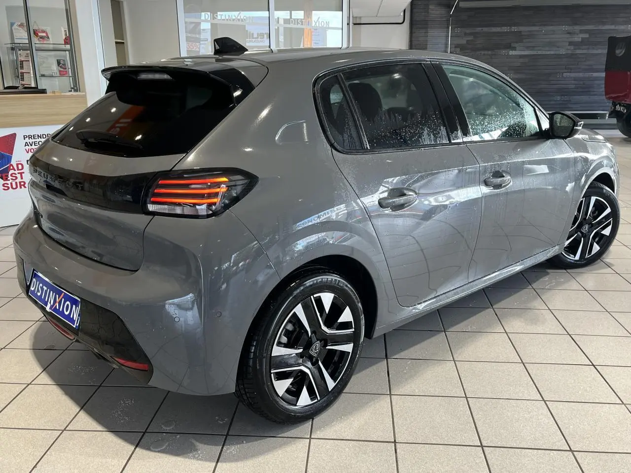 Peugeot 208 gris clair sélénium vue 3/4 arrière droit, feux arrière LED 3 griffes et jantes alliage diamantées.