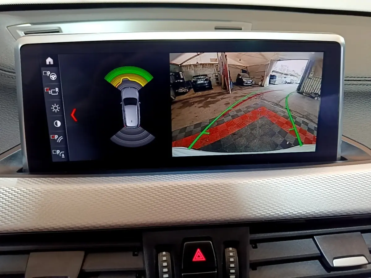 Écran tactile intérieur montrant la caméra de recul et les capteurs de stationnement du BMW X1 blanc 2022.