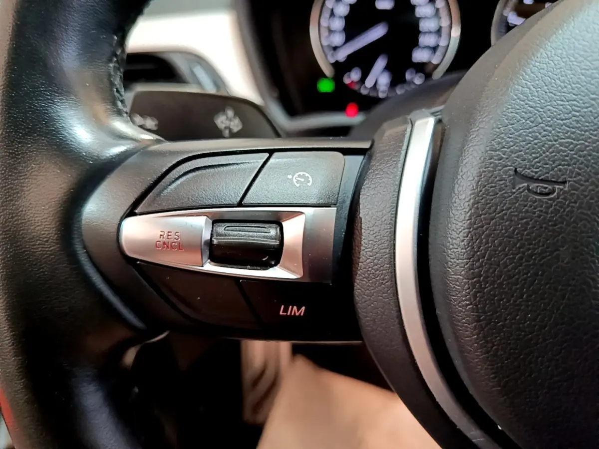 Gros plan sur les commandes du régulateur de vitesse au volant cuir noir du BMW X1 blanc sDrive18i M Sport 2022.