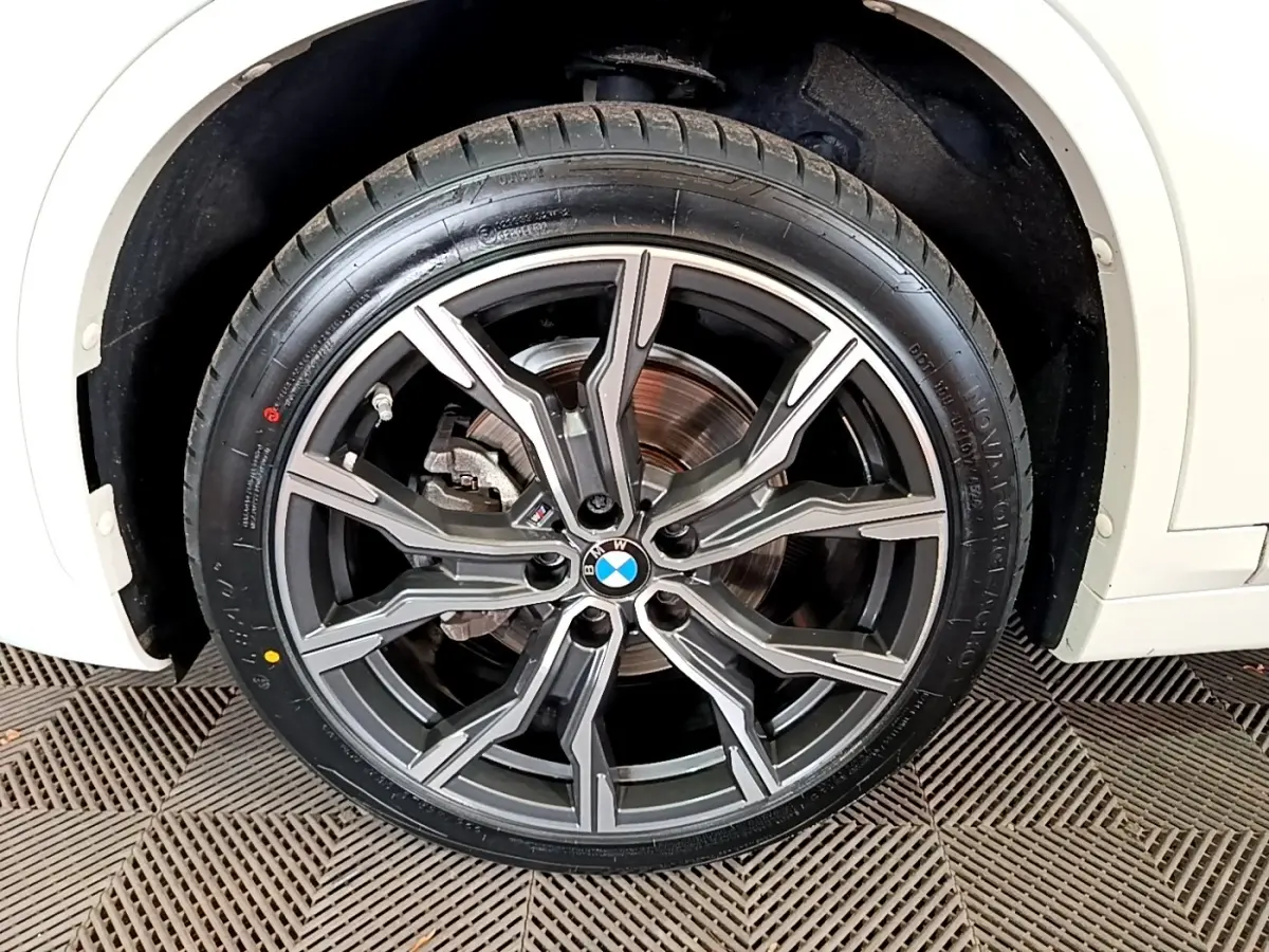 Gros plan sur la roue avant droite d’un BMW X1 blanc, jante alliage M Sport à design moderne et logo BMW central.