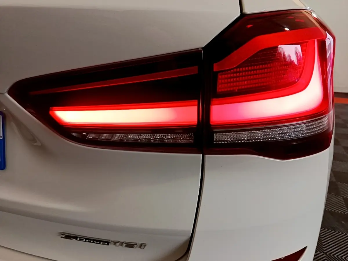 Gros plan sur le feu arrière droit rouge d’un BMW X1 blanc sDrive18i M Sport 2022.
