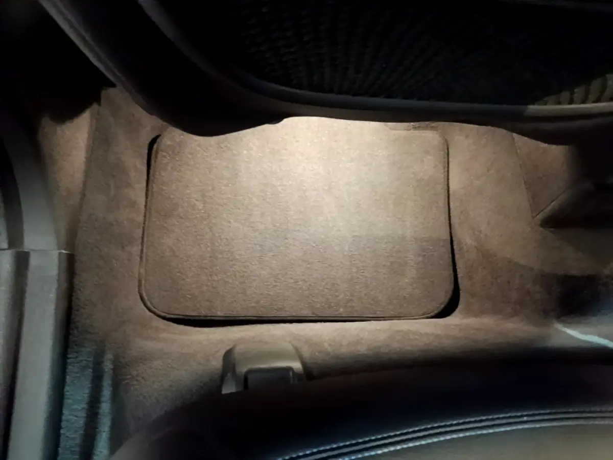 Plancher côté passager avant avec tapis noir et partie inférieure du siège dans un BMW X1 blanc.