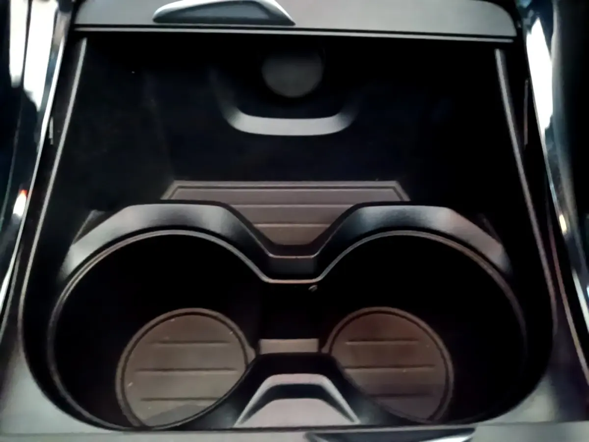 Gros plan sur les porte-gobelets noirs au centre de la console intérieure d’une BMW X1 blanche.