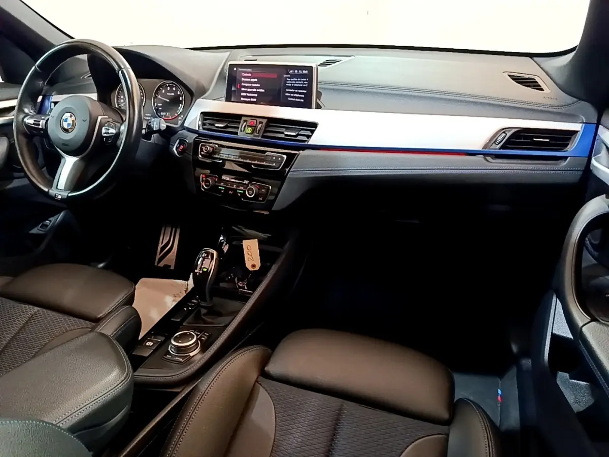 Vue intérieure avant de la BMW X1 sDrive18i M Sport 2022, tableau de bord avec écran tactile 8,8 pouces et volant cuir multifonctions.