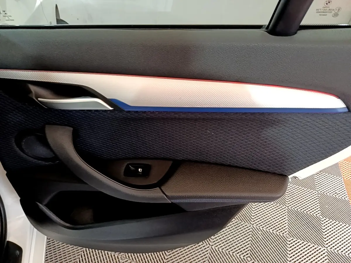 Détail de la porte côté gauche de la BMW X1 sDrive18i M Sport 2022, avec insert blanc et tissu noir texturé.