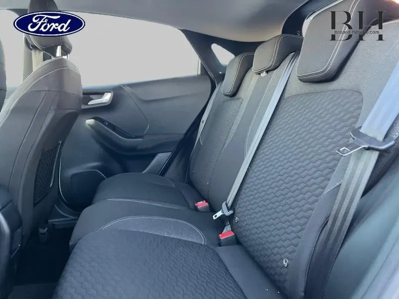 Vue latérale intérieure montrant les sièges arrière noirs en tissu du Ford Puma blanc de 2022.