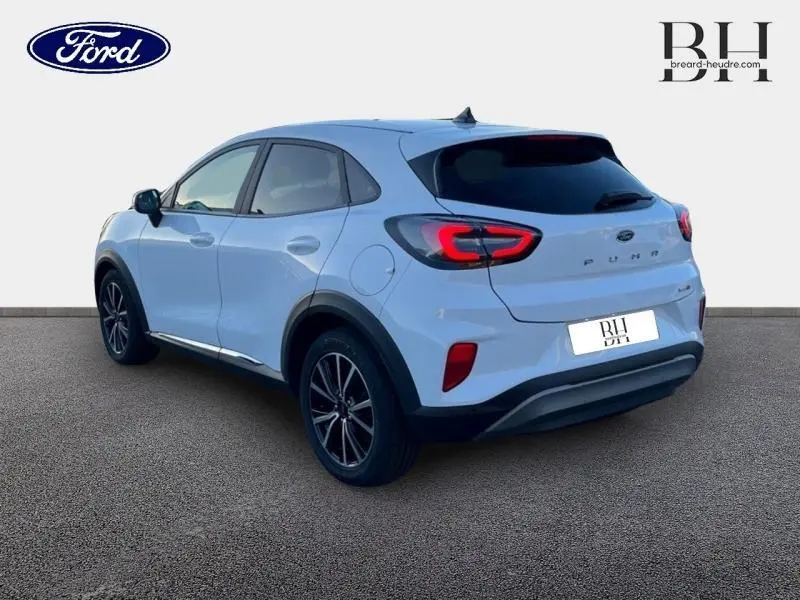 Vue 3/4 arrière droite du Ford Puma blanc avec jantes alu noires et feux arrière LED allumés.