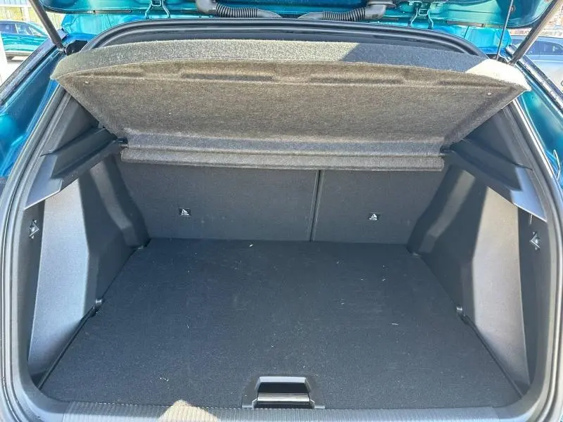 Coffre ouvert vu de l'arrière d'un Peugeot 2008 1.2 Hybrid 145ch Allure bleu Obsession, montrant l'espace de chargement vide.