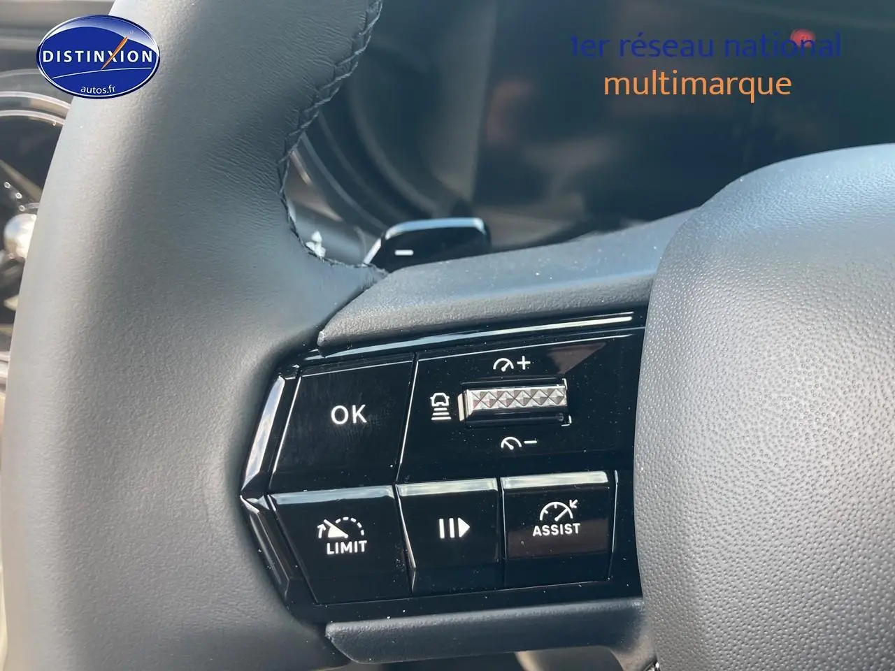 Gros plan sur les commandes au volant d'une Alfa Romeo Junior 1.2 hybride grise, avec boutons de régulateur et assistance.