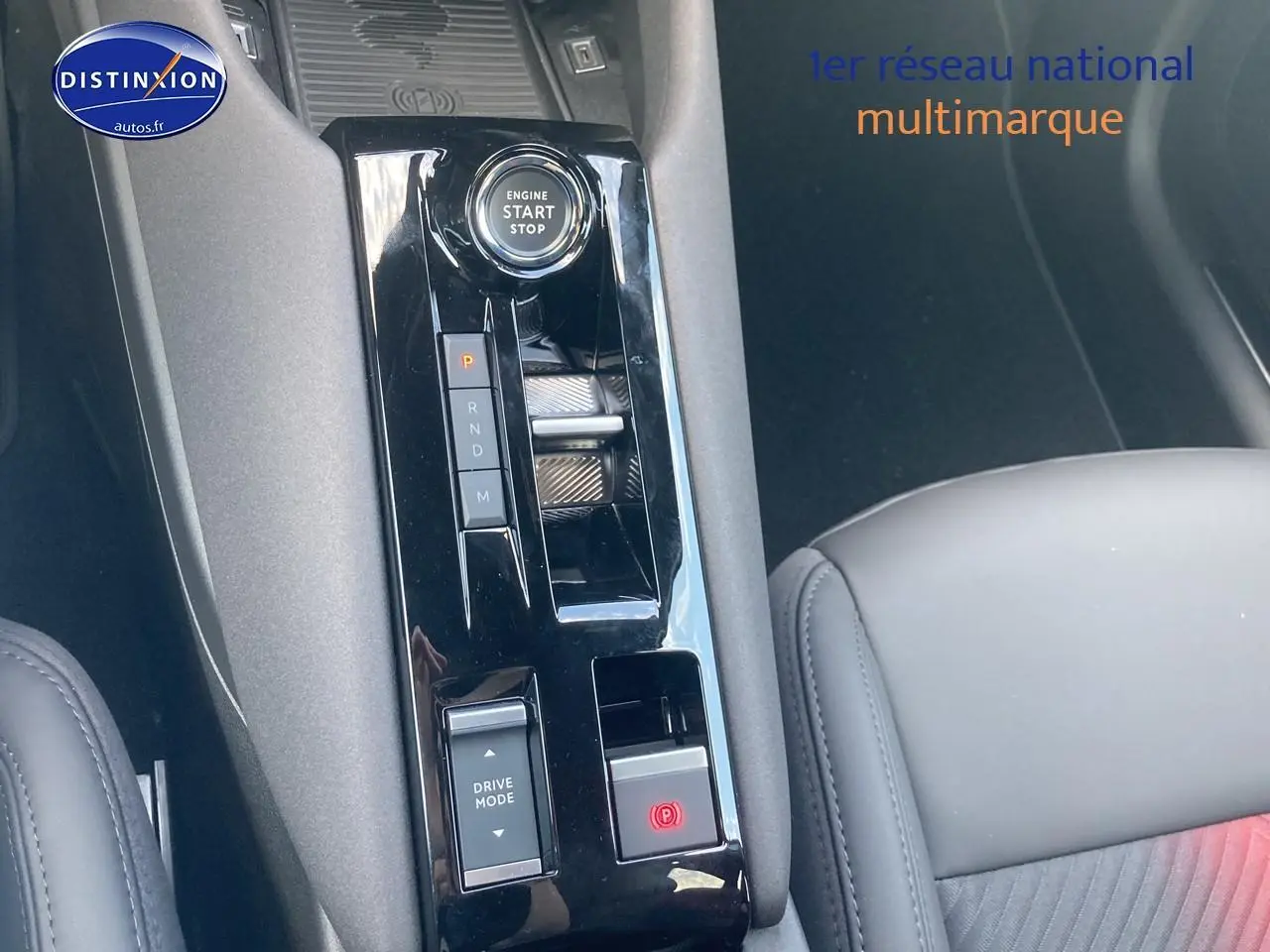Vue rapprochée de la console centrale noire brillante de l'Alfa Romeo Junior 1.2 hybride avec bouton start et commandes de boîte auto.