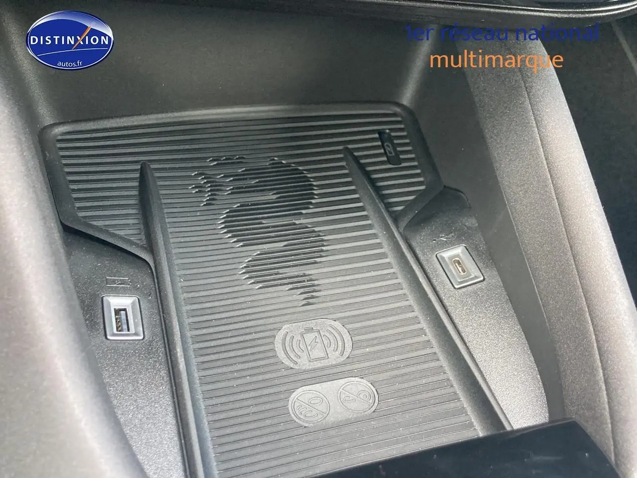 Gros plan sur la zone de charge à induction avec logo Alfa Romeo, entourée de ports USB, intérieur noir.
