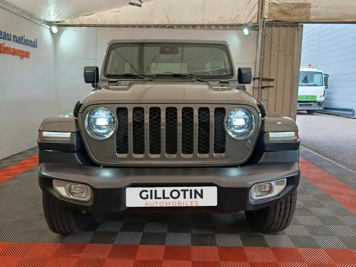 Vue frontale d'un Jeep Wrangler gris foncé avec phares LED allumés et calandre à sept barres verticales.