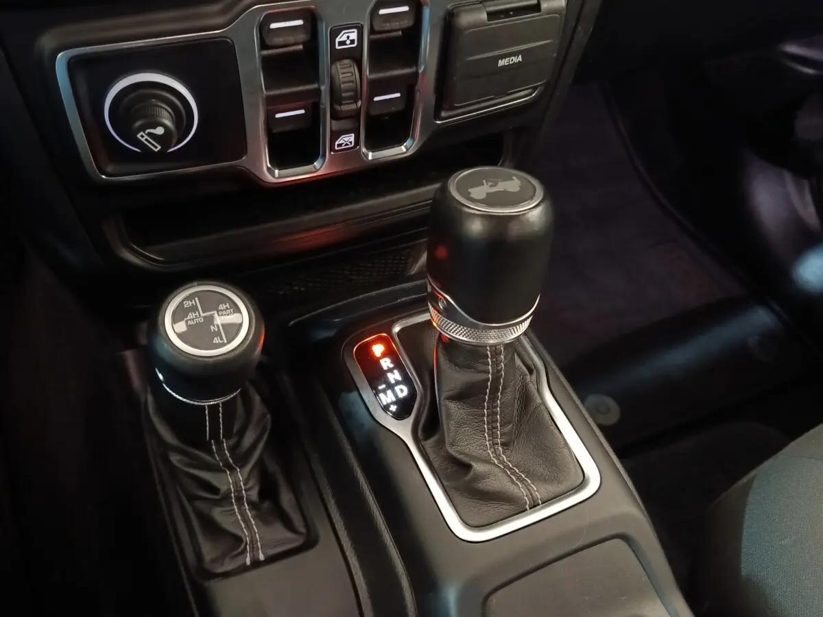 Gros plan sur le levier de vitesses automatique et la commande 4x4 du Jeep Wrangler gris foncé, intérieur noir.