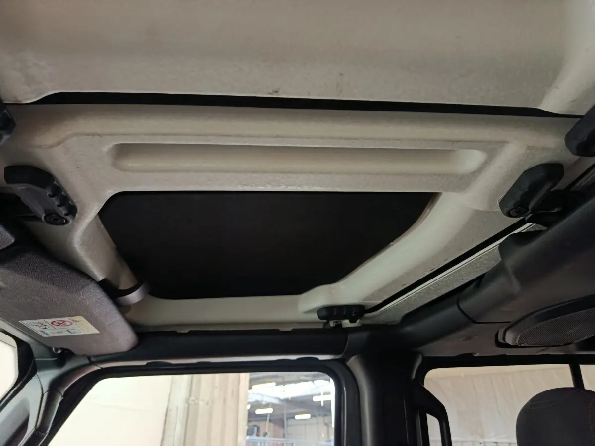 Vue intérieure du toit cabriolet manuel beige et noir du Jeep Wrangler gris foncé 2022, côté conducteur.