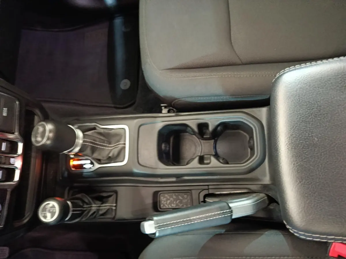 Vue plongeante sur la console centrale noire du Jeep Wrangler 2022 avec levier de vitesses et frein à main cuir.