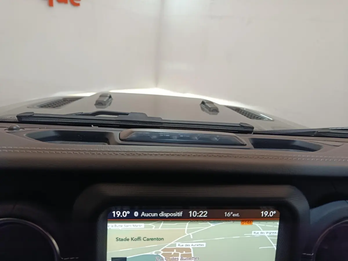 Vue intérieure centrée sur l'écran tactile de navigation du tableau de bord d'une Jeep Wrangler gris foncé.
